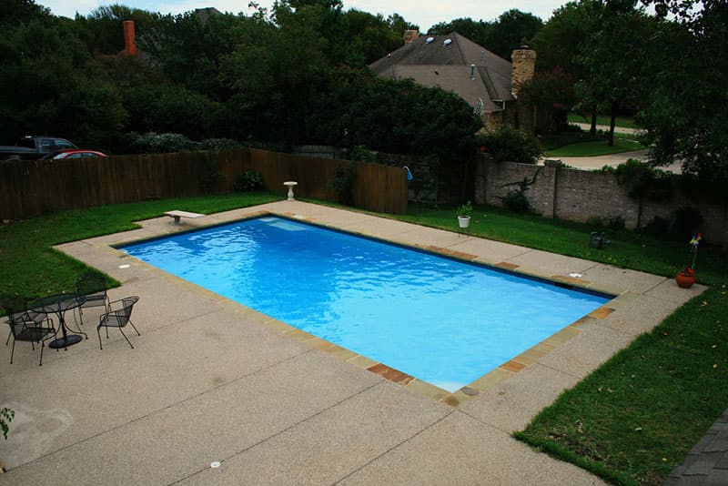 A traditional rectangle diving pool, Oklahoma coping and a large washed aggregate deck set in Corinth, Texas. This swimming pool was built for entertaining.