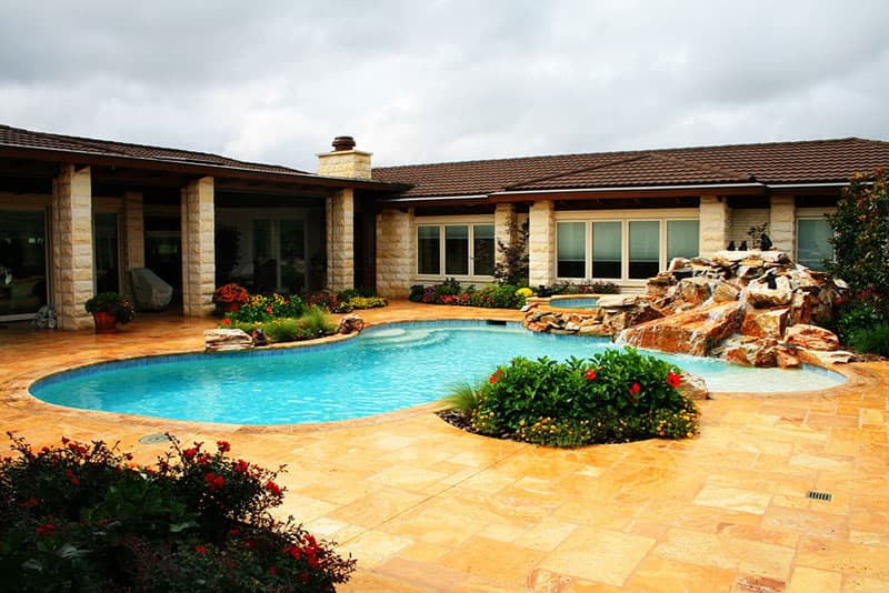 This Argyle, Texas swimming pool was designed with a unique flare of elegance in mind. The waterfalls are constructed of shisk boulders, the decking and pool coping are Turkish travertine and the interior finish is a light blue pebble finish.