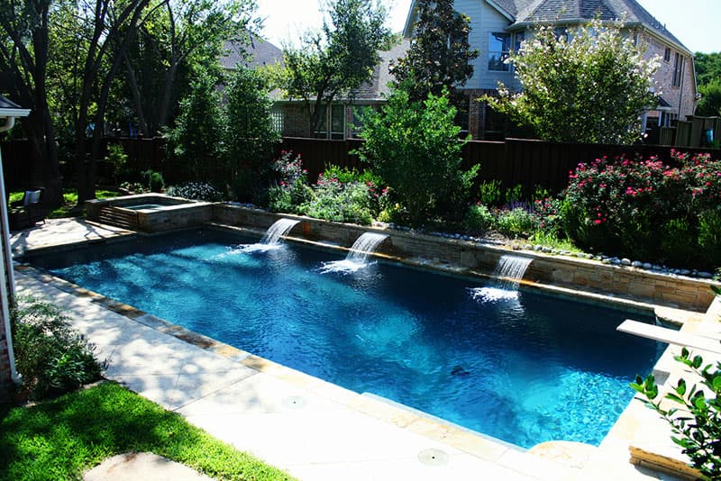 A more traditional look was the plan for this Southlake, Texas swimming pool/spa. The designer utilized ; stamped concrete decking, Oklahoma flagstone for the coping and in an irregular pattern on the raised beam, 3 stainless steel sheer descents, a recessed diving board and an elevated spa to achieve this design.