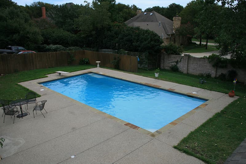 This Shady Shores, Texas swimming pool features stamped concrete decking, Oklahoma flagstone coping and a midnight blue aggregate finish interior