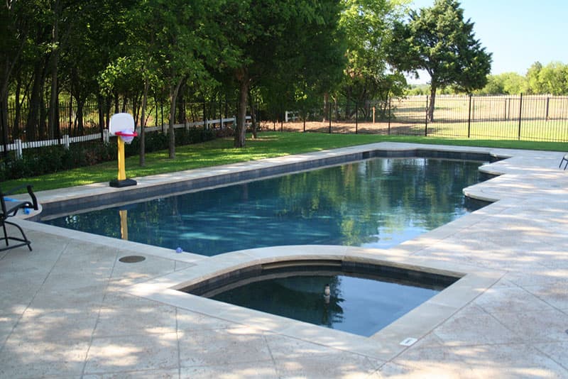 This Shady Shores, Texas swimming pool is located in the Cielo Ranch area and features a patterned stamped concrete deck, tumbled travertine coping, a pool level spa and pebble interior finish.