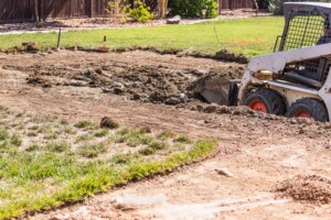 Picture of a skid steer digging in the back yard.