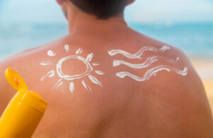 A man on the beach with sunscreen on his back.