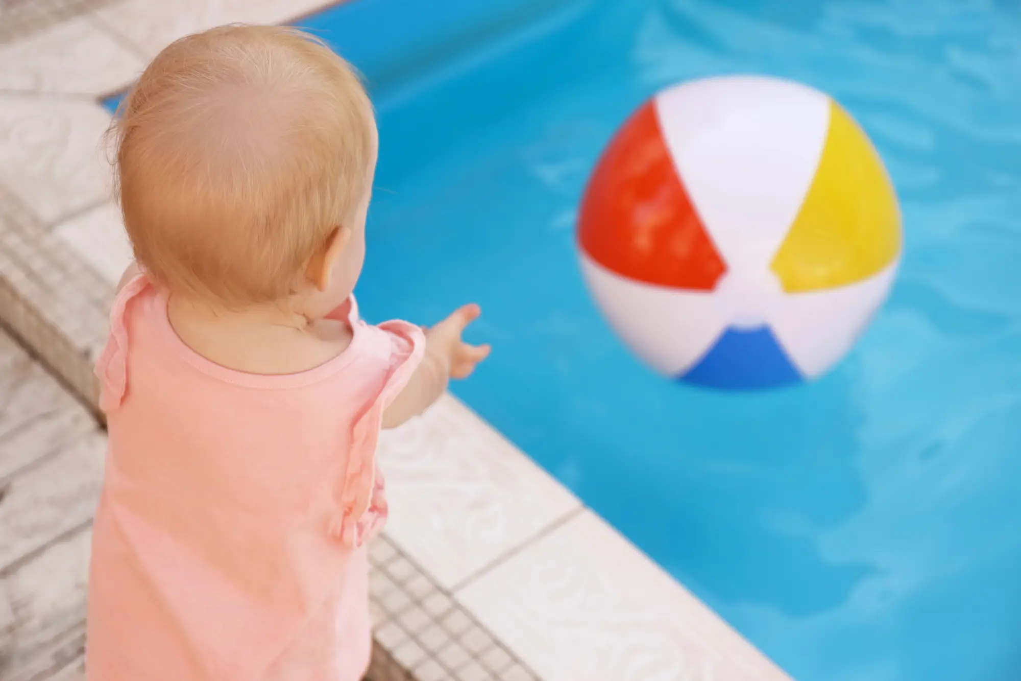 Picture of a toddler reaching for a pool ball.