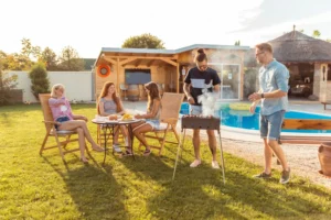 Picture of a group of young adults grilling in the backyard next to their pool.