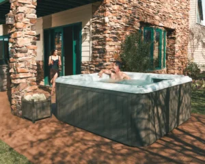Picture of a wife bringing out cold drinks to her husband who is sitting in a hot tub.